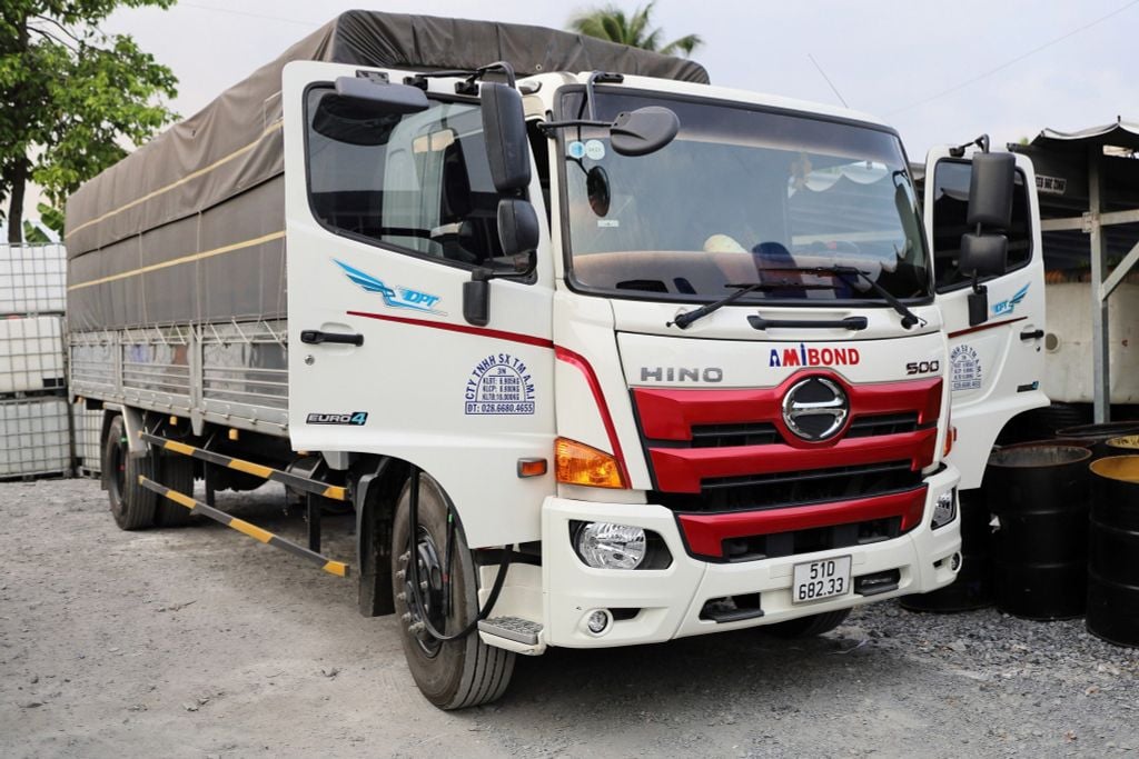 Xe tải Hino 500 thùng mui bạt màu trắng đỏ đỗ trong bãi, thùng hàng phủ bạt kín